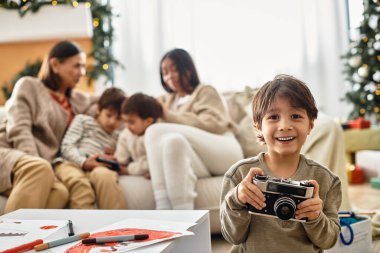 Mutlu bir aile, güzel dekore edilmiş bir Noel ağacının yanında, elinde kamerayla kaliteli vakit geçirmekten zevk alır.