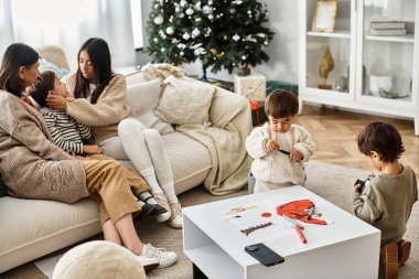 Mutlu bir aile Noel ağacının etrafında toplanır, birlikte güzel anların ve bayram ruhunun tadını çıkarırlar..