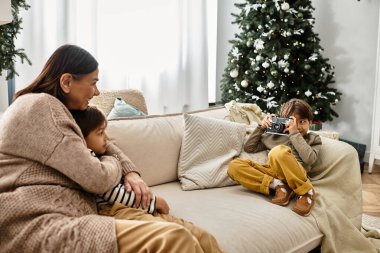 Neşeli bir aile Noel ağacının etrafında toplanır, kahkahaları paylaşır ve sıcak bir atmosferde anıları yakalar..