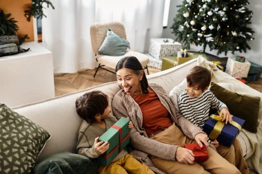 Neşeli bir aile güzel dekore edilmiş bir Noel ağacının etrafında toplanır, birlikte kahkaha ve hediyeleri paylaşırlar..