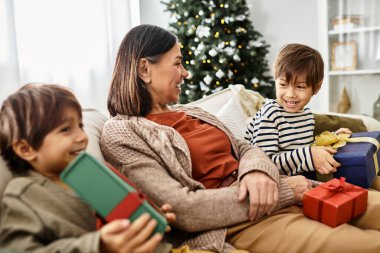 Güzel dekore edilmiş bir Noel ağacının etrafında toplanmış sıcak kalpli bir aile, kahkahalar ve hediyeler paylaşıyor..