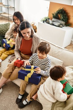 Aile üyeleri, Noel hediyelerini birlikte açmaktan keyif alır. Sıcak evlerinde kahkahalar ve sevgiyi paylaşırlar..