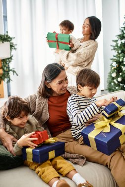 Mutlu bir aile toplanır, güzel dekore edilmiş bir Noel ağacının yanında hediyeleri açarken kahkahalarını paylaşırlar..