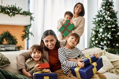 Neşeli bir aile Noel ağacının yanında toplanıyor, hediyelerini ve gülüşlerini modern kış inzivalarında paylaşıyorlar..