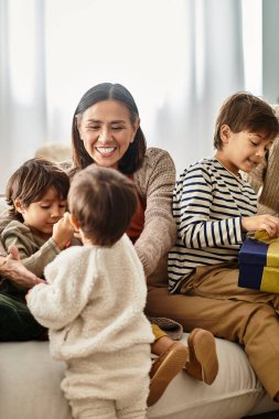 Mutlu bir aile, sıcak bir oturma odasında kahkaha ve hediyelerini paylaşarak eğlenir..
