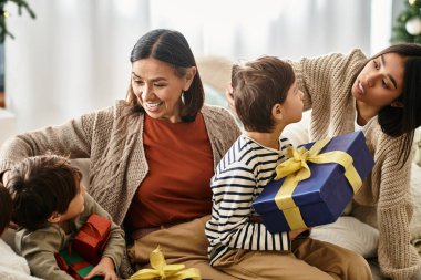 Mutlu bir aile, güzel dekore edilmiş bir odanın yanında Noel hediyelerini ve kahkahaları paylaşarak eğlenir..