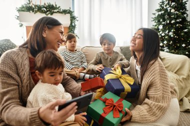 Aile üyeleri neşe ve kahkahayı paylaşırken güzel dekore edilmiş ağaçlarının renkli hediyelerini açıyorlar..