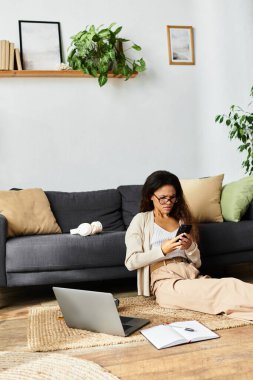 Rahat bir yaşam alanında, bir kadın yerde oturur, akıllı telefonunu dikkatle kullanır..