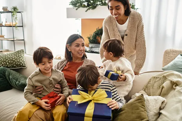 Mutlu bir aile, sıcak bir oturma odasında Noel hediyelerini ve kahkahaları paylaşıyor..