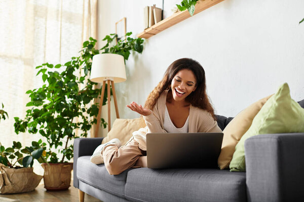 Женщина тепло улыбается, участвуя в оживленном онлайн чате в своем уютном жилом пространстве..