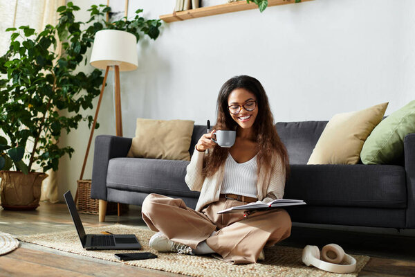 A woman sits on the floor, sipping coffee and reading a book, surrounded by greenery.