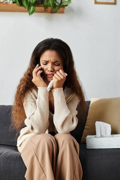 Женщина выглядит расстроенной, разговаривая по телефону, явно расстроенной и держащей салфетки..