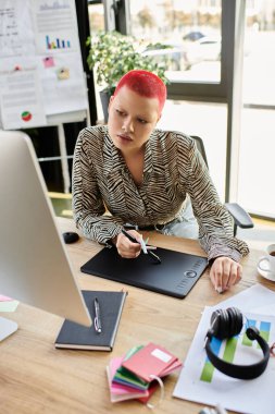Odaklanmış kel bir kadın masasında yenilikçi projeler üzerinde çalışırken tablet kullanıyor..