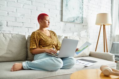 Kel bir kadının koltukta rahatça otururken işine odaklandığı huzurlu bir an..