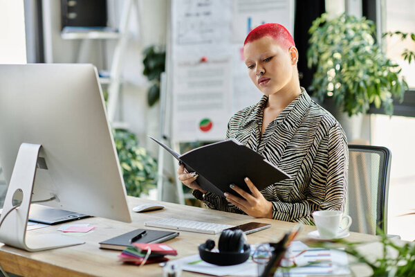 Лысая женщина с яркими рыжими волосами рассматривает документы, сидя за стильным столом.