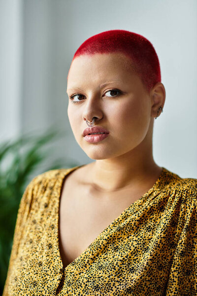A bald woman with red hair wears a stylish outfit while showcasing her unique beauty.
