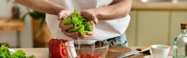 Kıvırcık saçlı genç bir adam modern mutfağında renkli bir salata yapıyor..