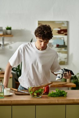 Yakışıklı bir genç adam taze bir salata yaratmaya odaklanır. Mutfağında hayat dolu ve sağlıklı bir hayat sürer..