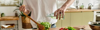 A young man with curly hair joyfully makes a fresh salad in his bright, contemporary kitchen. clipart