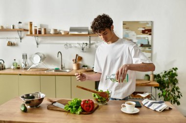 Yakışıklı genç bir adam modern bir mutfakta canlı bir salata hazırlıyor ve sağlıklı bir yaşam sağlıyor..