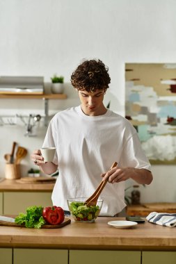 Yakışıklı genç bir adam şık mutfağında sağlıklı bir yaşam sürerken enerjik bir salata hazırlıyor..