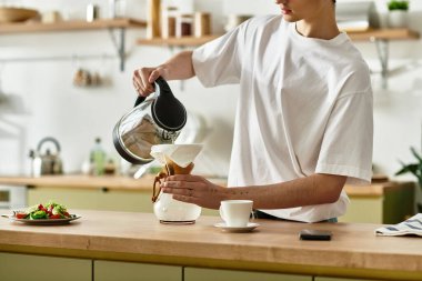 Amidst a bright kitchen, a young man with curly hair pours coffee, savoring the relaxing afternoon vibe. clipart