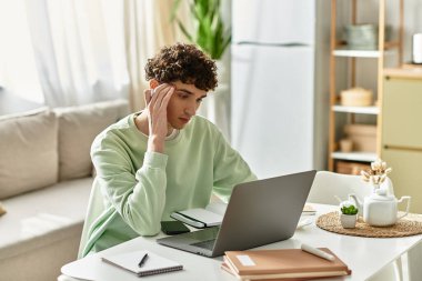 In a modern apartment, a young man with curly hair concentrates on his tasks while working from home. clipart