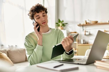 Yakışıklı genç bir adam modern dairesinden iş yapıyor, bir aramayı dengeliyor ve dikkatle notlar alıyor..