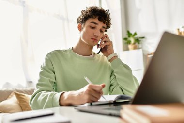 Yakışıklı bir genç adam, şık çalışma alanına notlar yazarken telefonda konuşuyor..