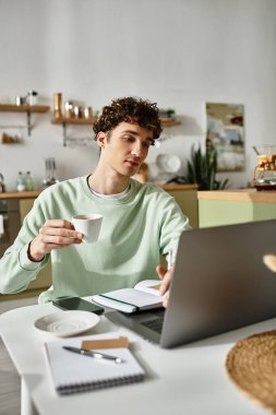 Genç ve yakışıklı bir adam kahvesini yudumlarken şık ve modern dairesinde özenle çalışıyor..