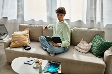 Yakışıklı genç adam modern dekorlarla çevrili şık evinde kitap okurken rahatlıyor..