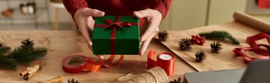 Sıcak bir ortamda, genç bir adam güzel paketlenmiş bir Noel hediyesi sunar..