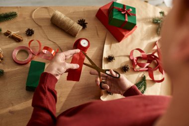 Sıcak bir ortamda, genç bir adam önümüzdeki Noel kutlamaları için hediyeler paketliyor..