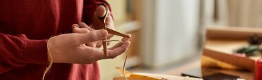 A young man carefully cuts twine for wrapping Christmas gifts in a warm, festive environment. clipart