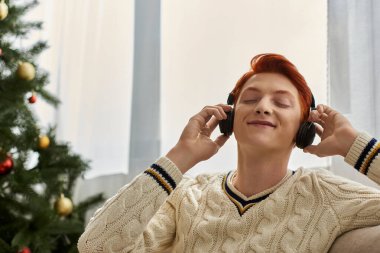 Genç bir adam müzik dinlerken ve Noel 'i kutlarken kendini neşeli ve rahat hisseder..