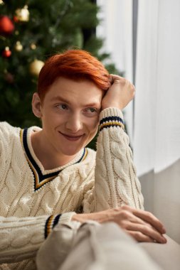 Neşeli genç bir adam pencerenin kenarında gevşiyor, bir gülümsemeyle Noel 'in sıcaklığını kucaklıyor..