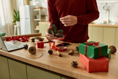 A young man is crafting festive Christmas decorations in a warm, inviting kitchen. clipart