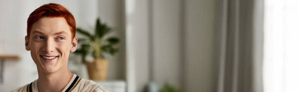 Веселый молодой человек с ярко-рыжими волосами наслаждается праздничным духом Рождества в помещении.