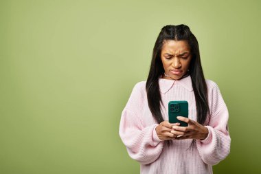 Şık ve kalın giysiler içinde genç bir kadın akıllı telefonuna odaklanmış, düşüncelere dalmış..