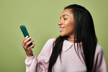 Genç kadın telefonuyla meşgul olurken gülümsüyor, şık sonbahar kıyafetlerini sergiliyor..