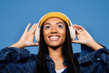 Genç bir kadın, rahat, şık sonbahar kıyafetiyle müzik dinlerken ışıl ışıl gülümser..