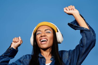 Şık sonbahar kıyafetleri içinde, genç bir kadın müzik dinlerken neşeyle dans ediyor..