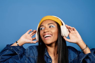 Sıcak bir bere takan ve şık giyinen neşeli genç bir kadın müziği zevkle tecrübe eder..