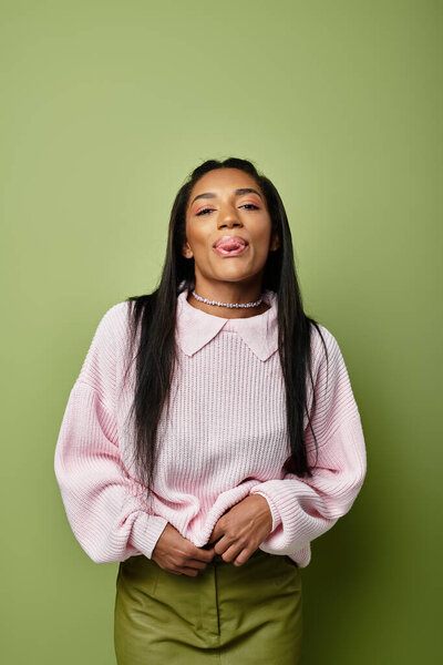 Молодая женщина демонстрирует свой модный осенний наряд, игриво высунув язык.