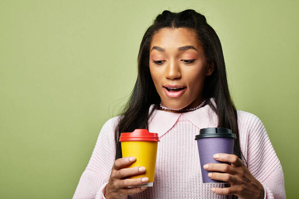 Молодая женщина, горячо одетая, улыбается в восторге, держа в руках две разноцветные чашки кофе.