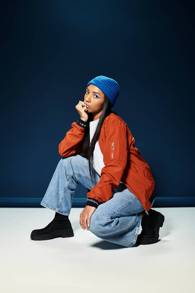 A young woman dressed in vibrant autumn clothing crouches gracefully with style and poise.