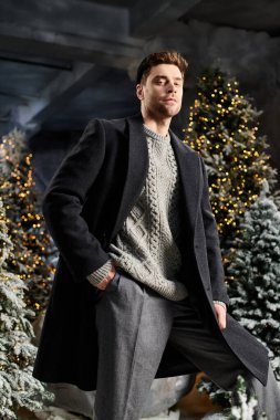 A well-dressed man enjoys the festive atmosphere surrounded by snowy trees adorned with twinkling lights. clipart