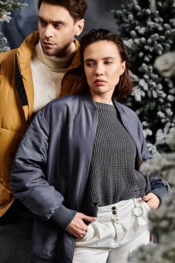 Güzel bir çift, karla kaplı çam ağaçlarının yanında ısınarak Noel ruhunu kutluyor..