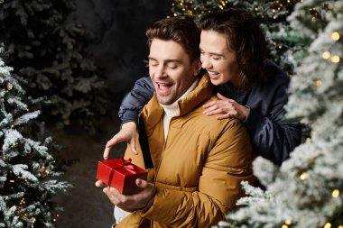 Mutlu bir çift, karlı çamların yanında, aşkı ve Noel 'in sihrini kutlayan sıcak bir anın tadını çıkarır..