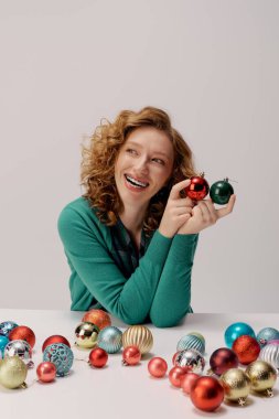 A cheerful young woman posing cheerfully amid colorful ornaments in a festive setting. clipart